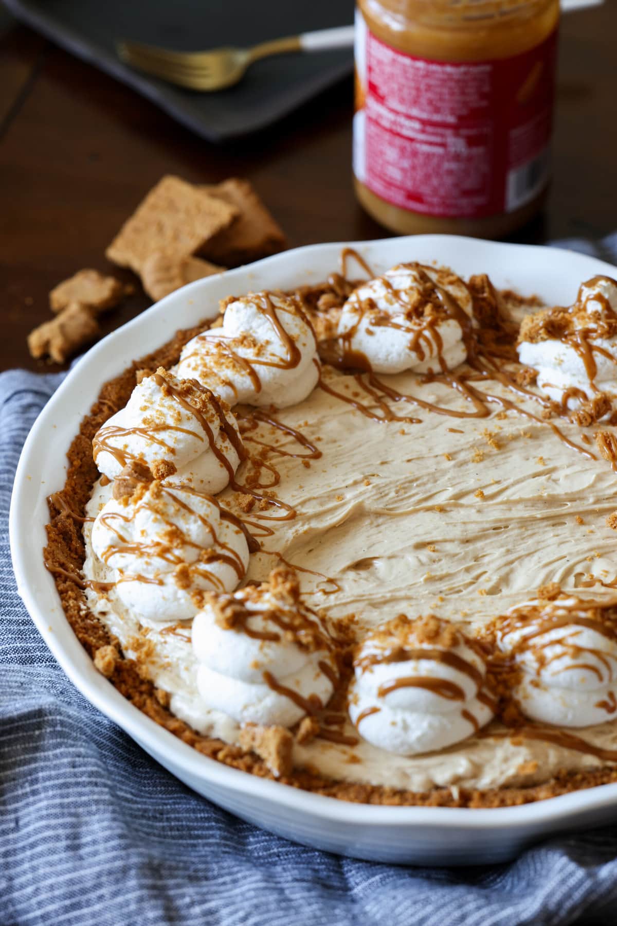 Cookie Butter pie in a white pie plate topped with whipped cream, crushed cookies, and drizzled Biscoff spread