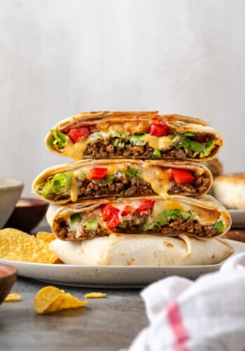 Crunch wraps cut in half and stacked on a plate.