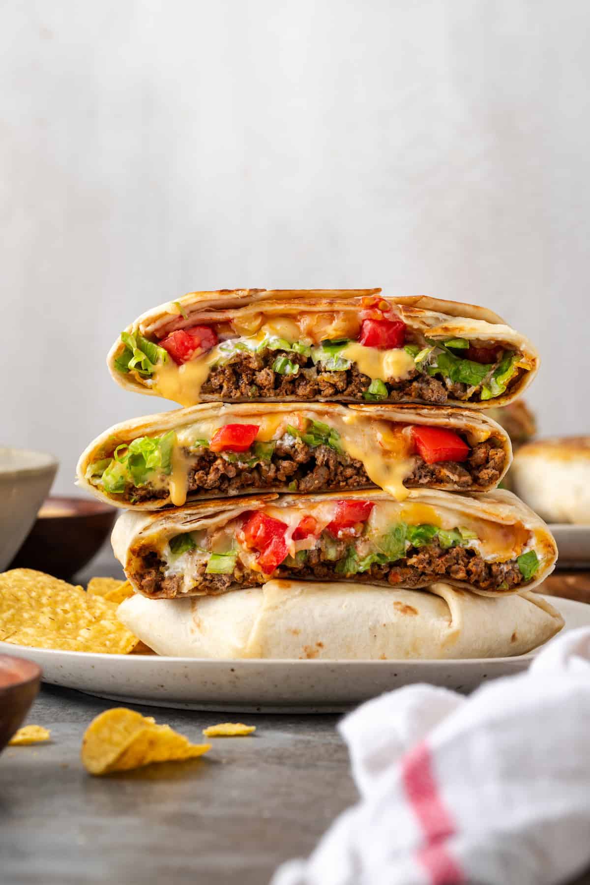 Crunch wraps cut in half and stacked on a plate.