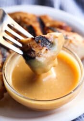 A piece of grilled chicken on a fork coated in homemade chick-fil-a chicken sauce