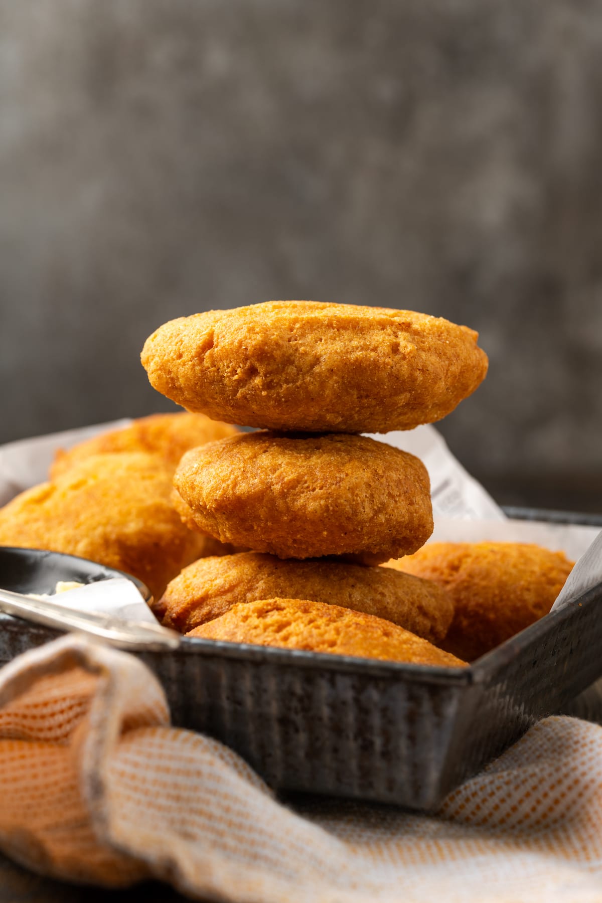 Side view of a stack of hot water cornbread in a basket.