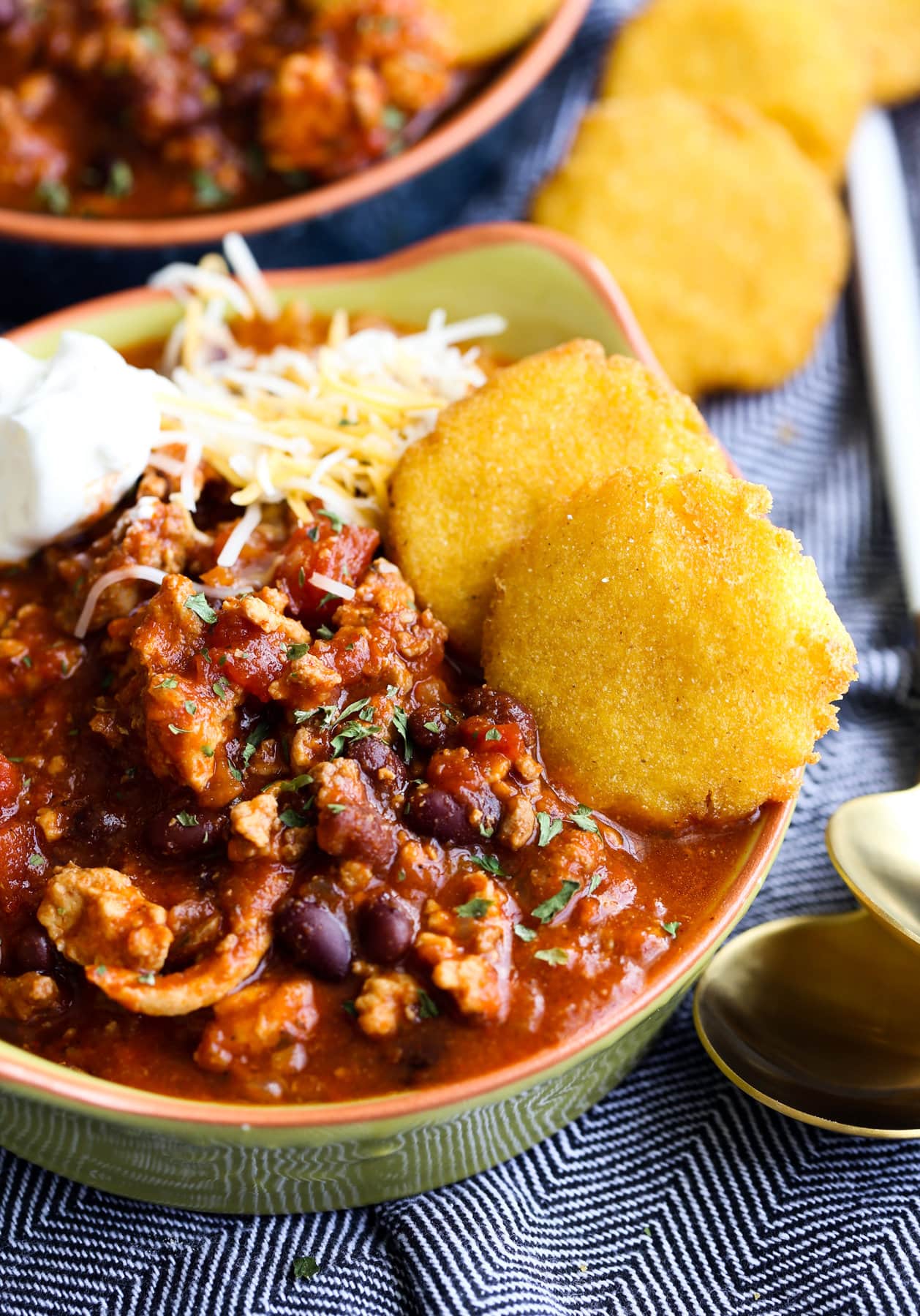 a bowl of chili with hot water cornbread on the side