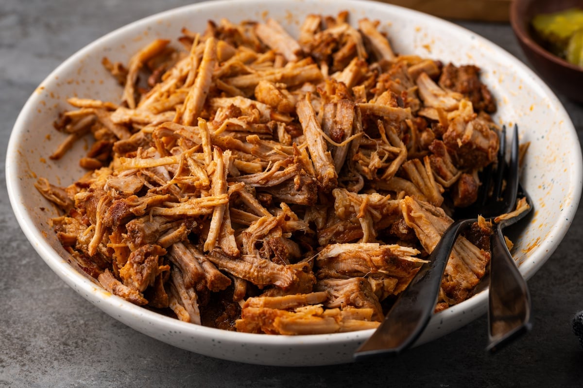 A bowl of Instant Pot pulled pork with two black forks.