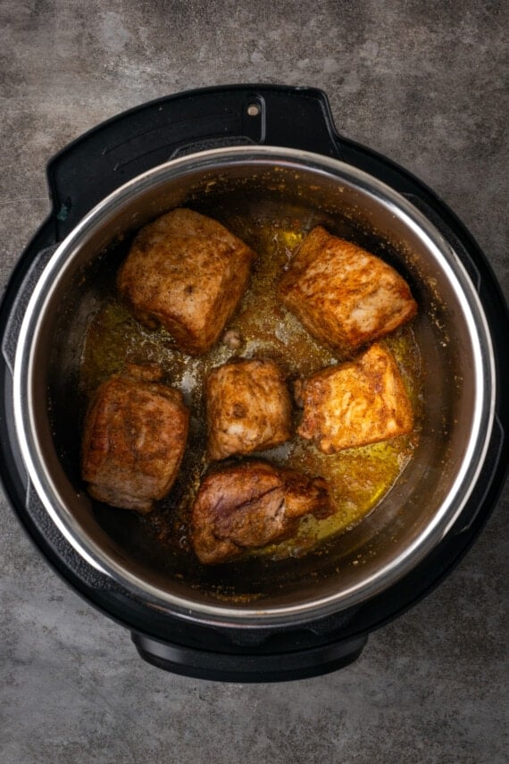 Seasoned pork butt pieces browning inside the instant pot.