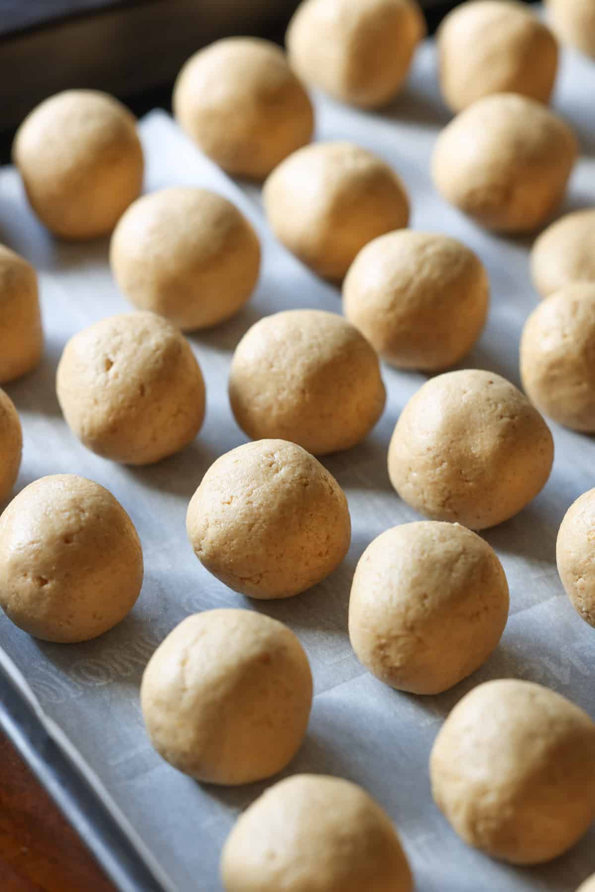 peanut butter balls rolled into balls on a parchment lined baking sheet before being dipped into chocolate