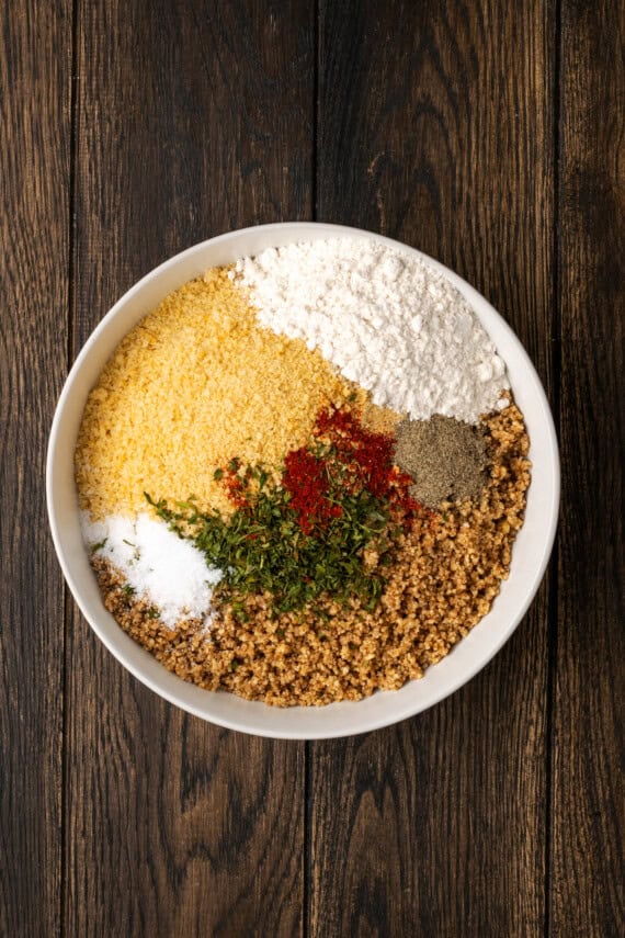 Breading and seasoning added to a bowl.