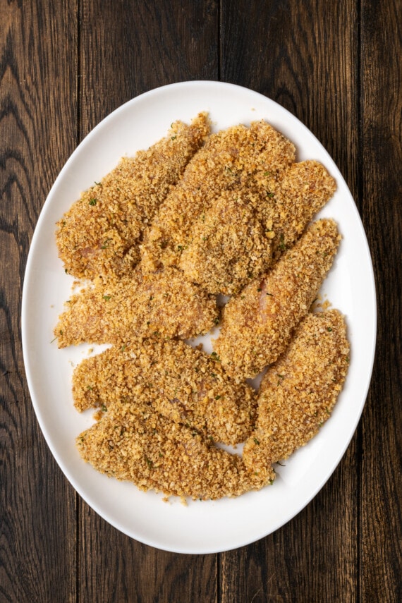 Chicken tenders coated with crushed pecan coating on a plate.