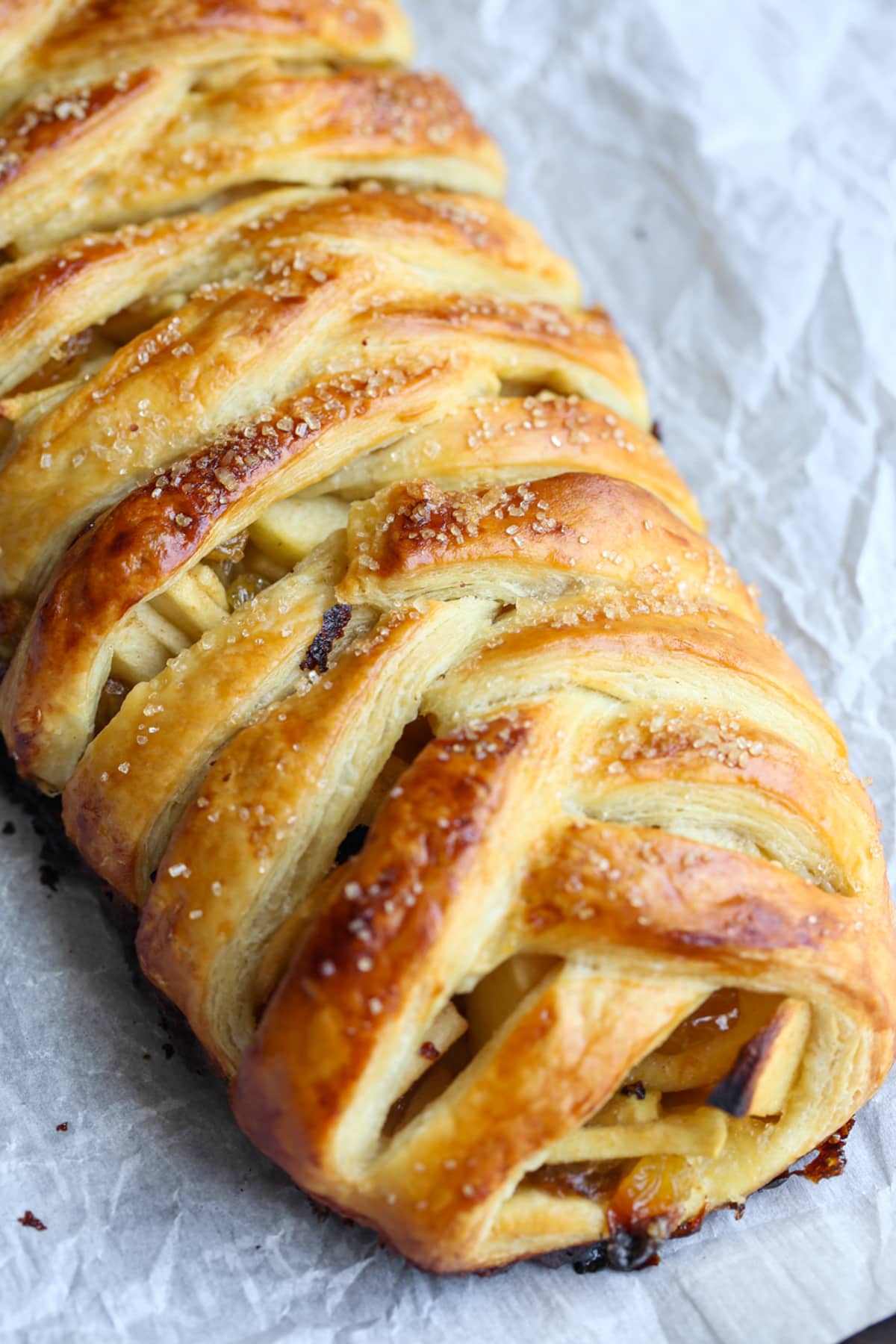 A baked apple strudel with a braided pastry on a baking sheet