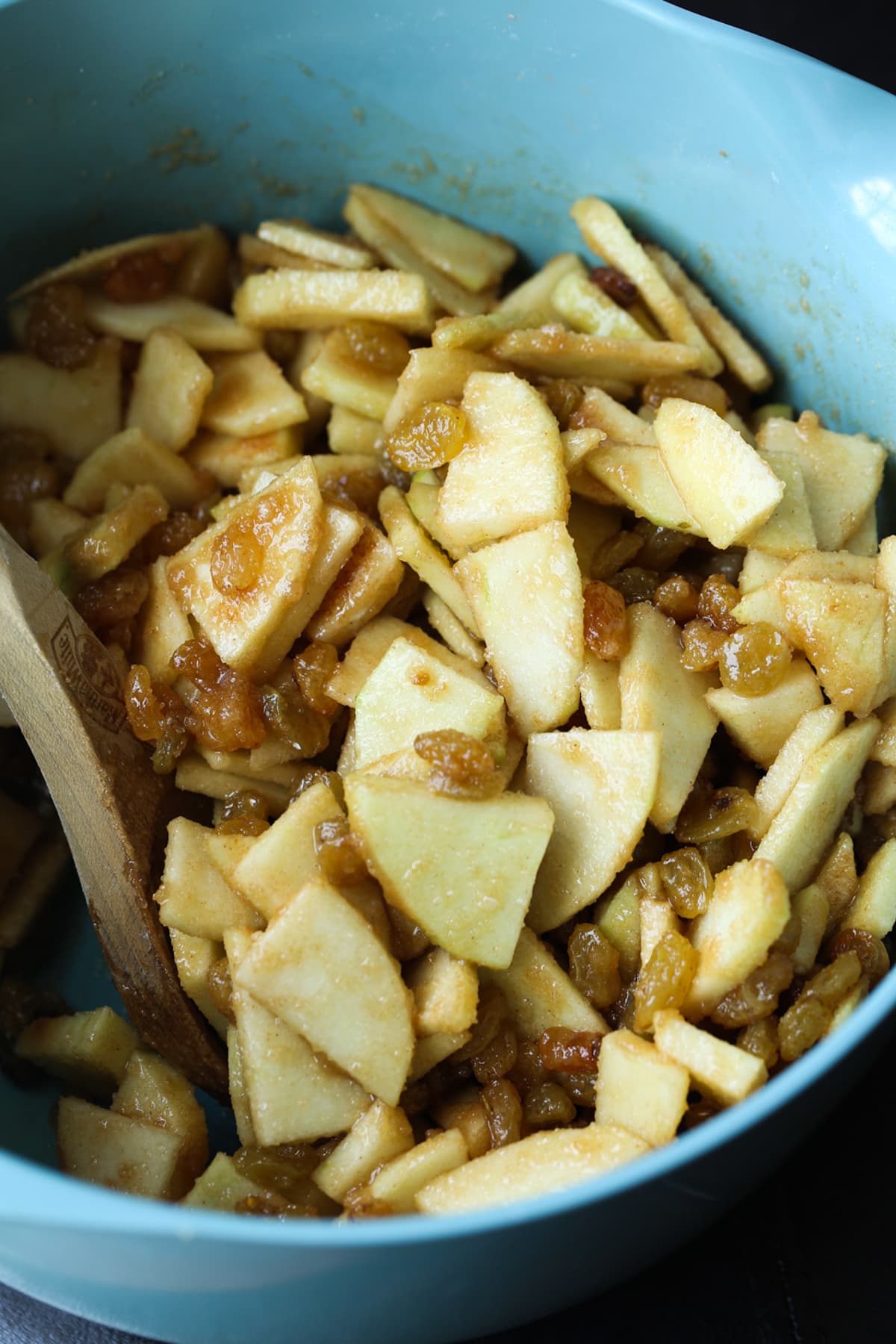 A blue bowl filled with chopped sliced apples coated in cinnamon sugar