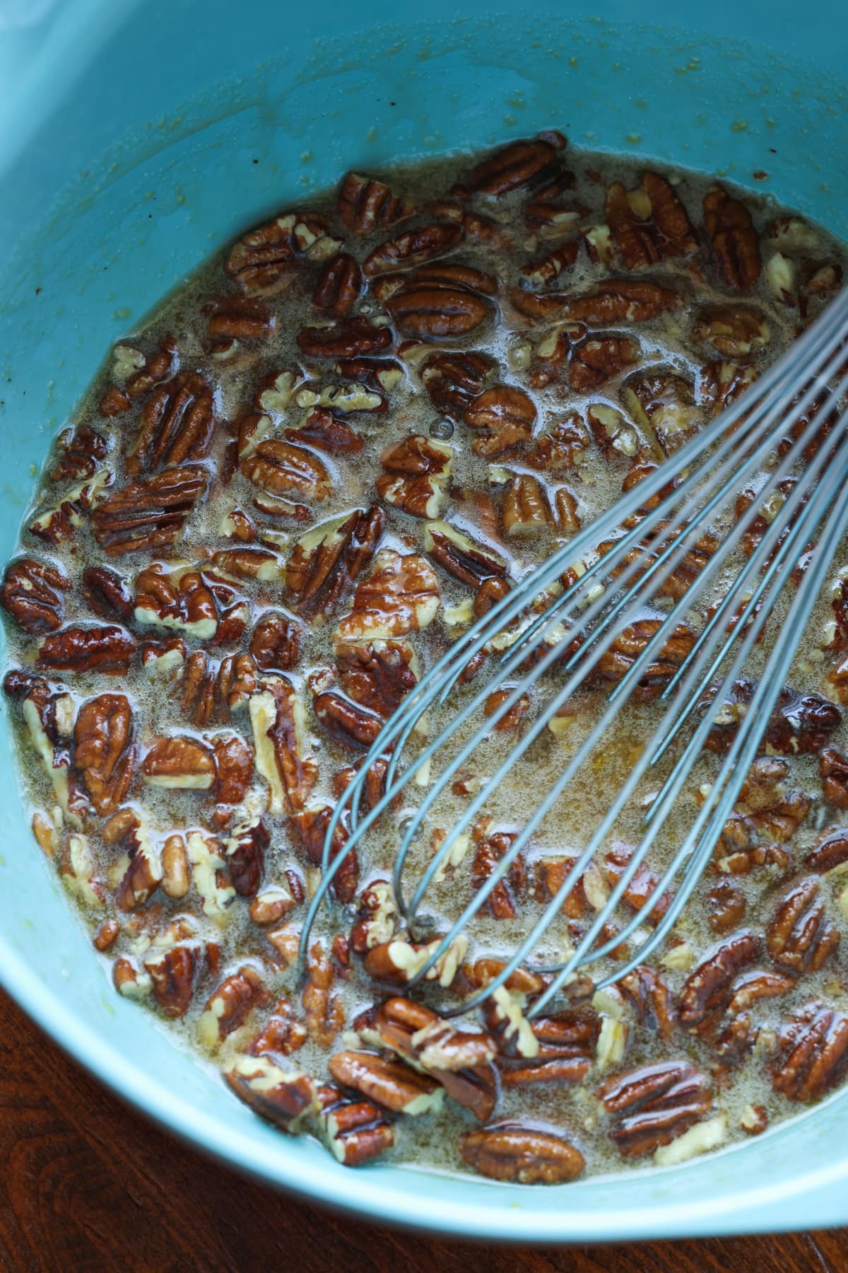 Pecan tart mixture in a blue bowl with a whisk