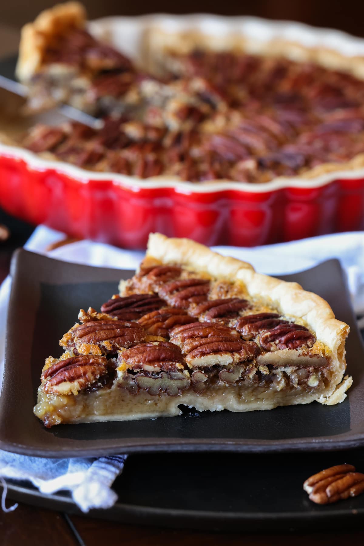 Pecan Tart slice on a black plate in front of a tart pan