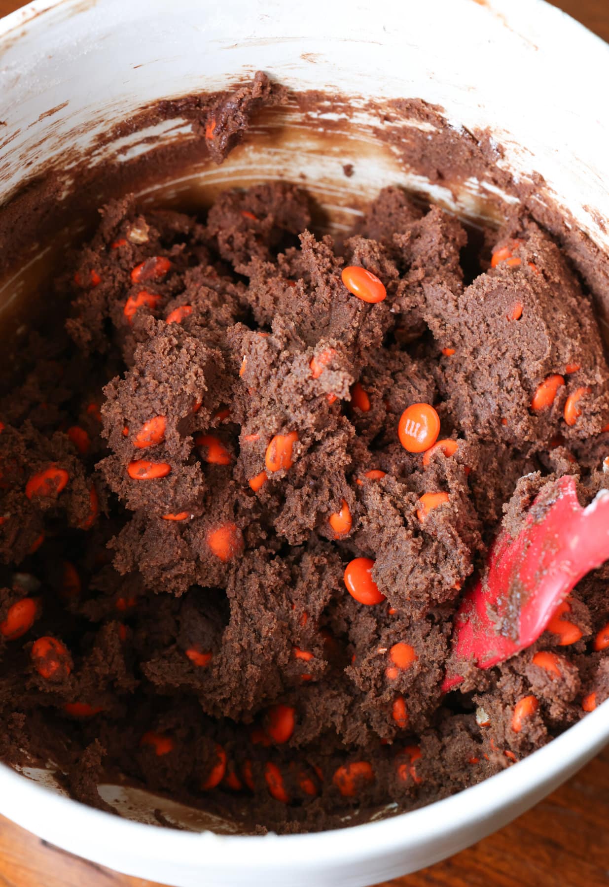 chocolate cookie dough in a mixing bowl with orange M&Ms