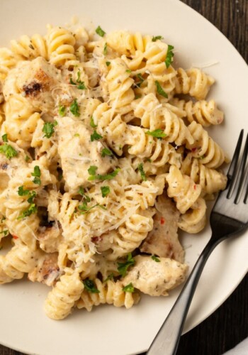 Overhead view of a bowl of Buffalo Wild Wings garlic parmesan chicken pasta with a fork.