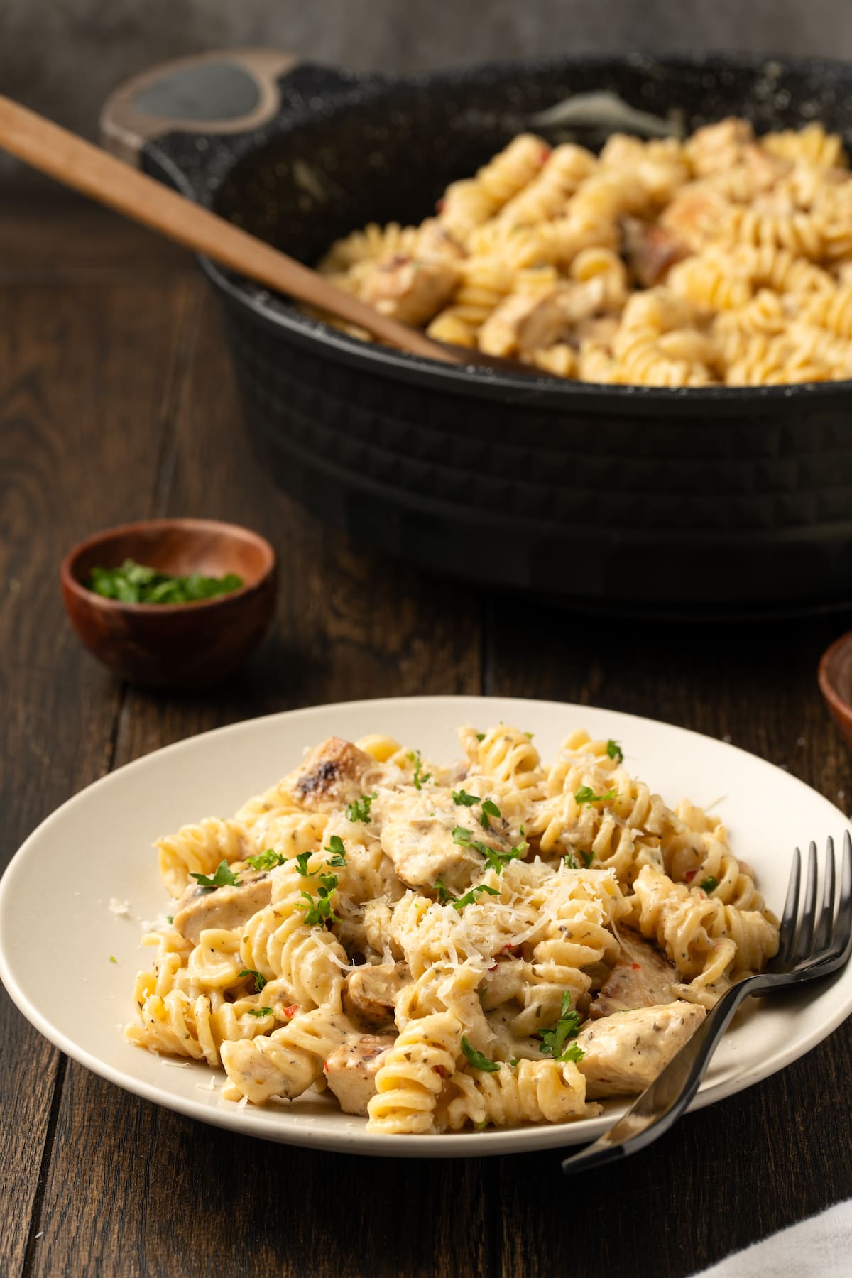 A bowl of Buffalo Wild Wings garlic parmesan chicken pasta next to a skillet.