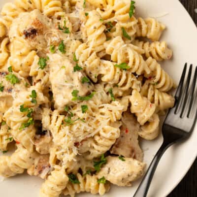 Overhead view of a bowl of Buffalo Wild Wings garlic parmesan chicken pasta with a fork.