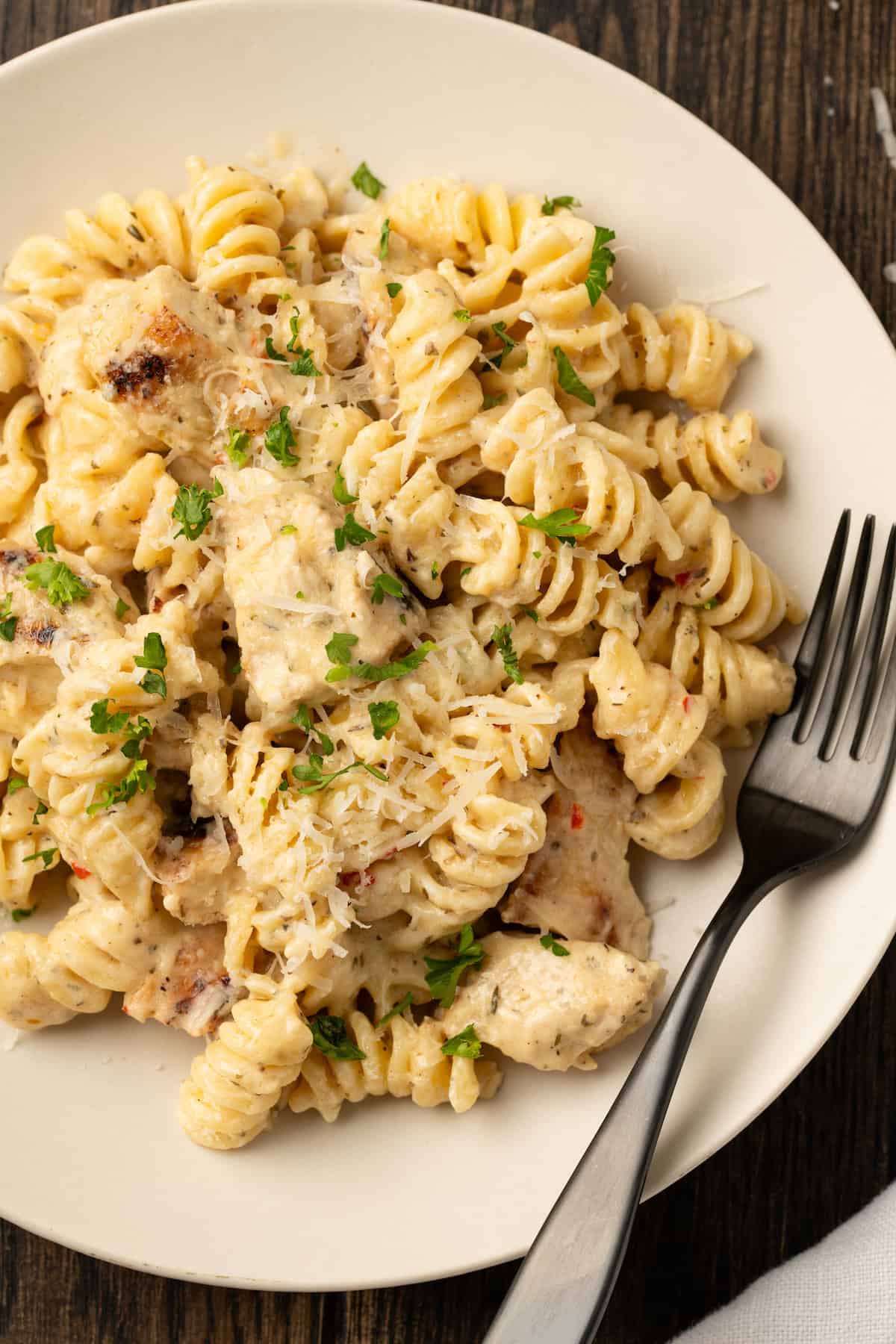 Overhead view of a bowl of Buffalo Wild Wings garlic parmesan chicken pasta with a fork.