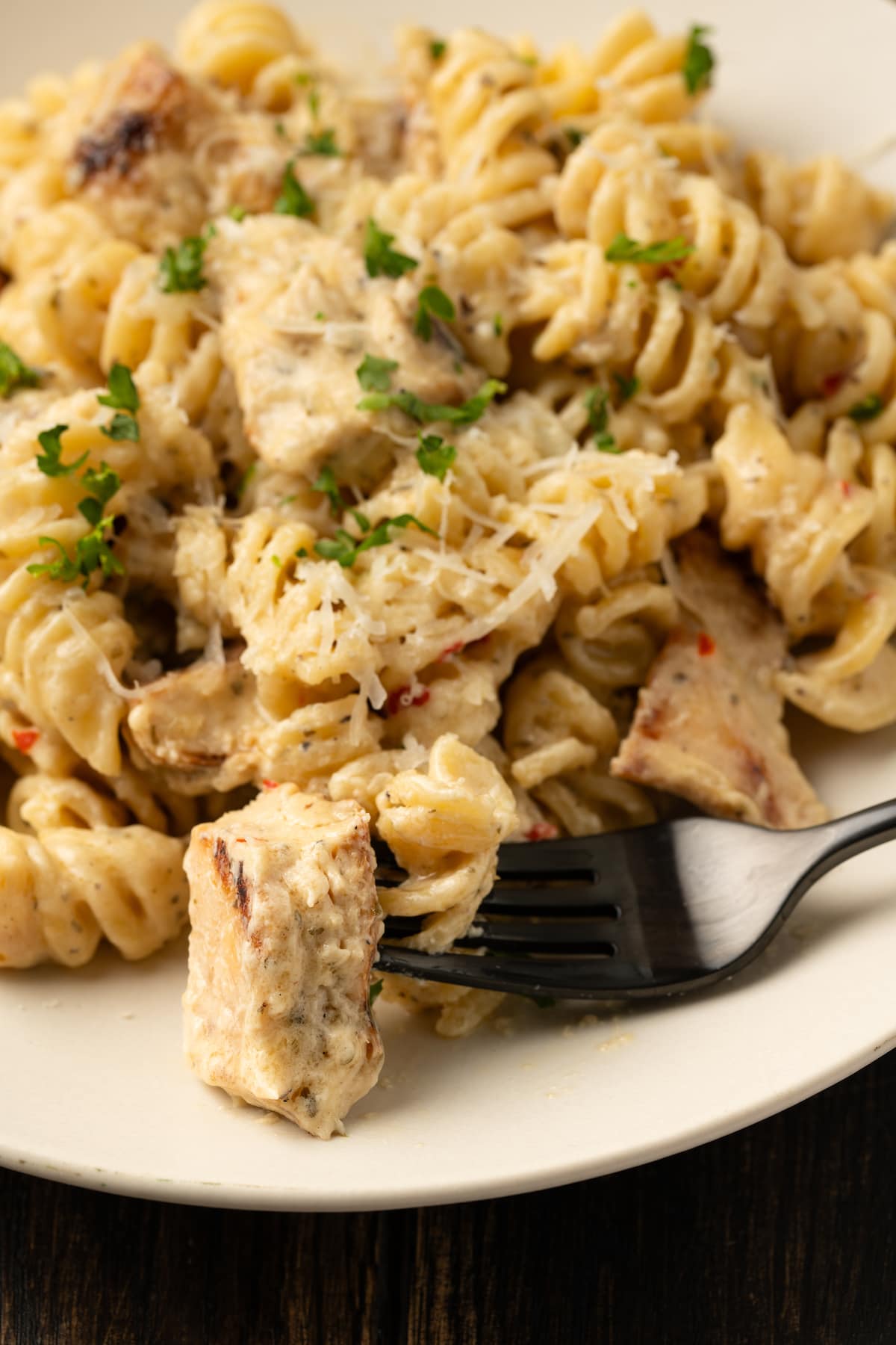 Close up of a bowl of Buffalo Wild Wings garlic parmesan chicken pasta with a fork.
