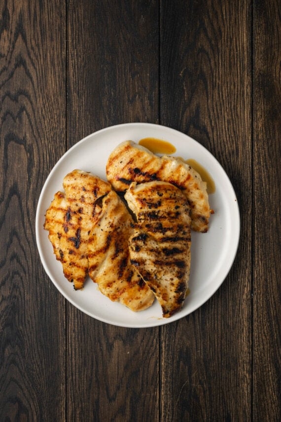 Overhead view of two grilled chicken breasts on a plate.