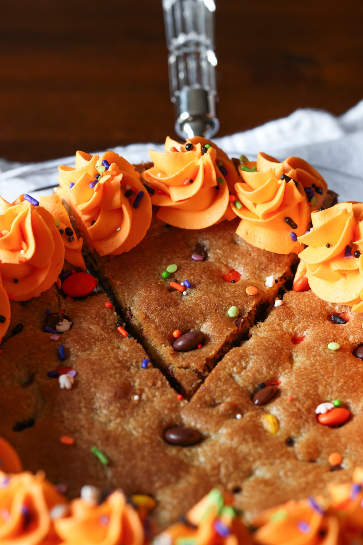 A slice of Halloween cookie cake with orange frosting cut and served with a spatula.