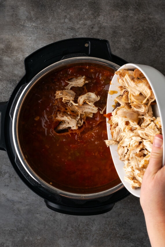 Shredded chicken added back into the Instant Pot with the broth ingredients.