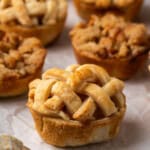 Close up of mini apple pies on a piece of parchment paper.