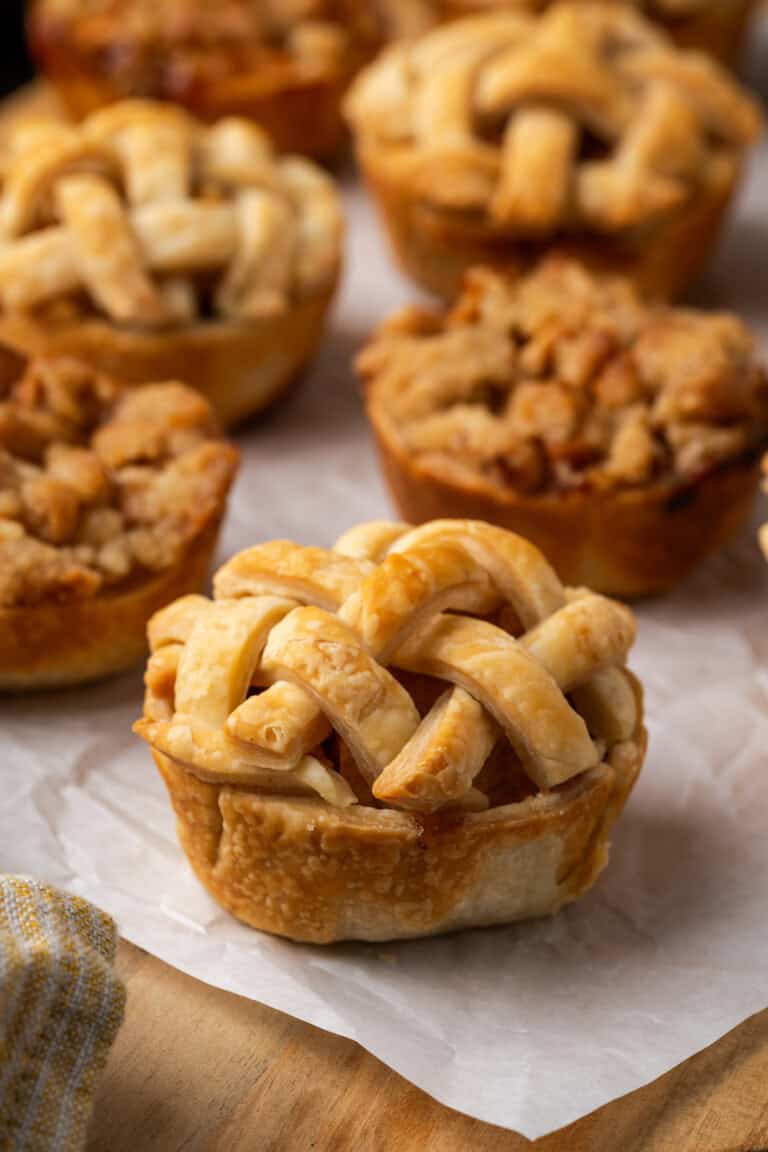 Close up of mini apple pies on a piece of parchment paper.