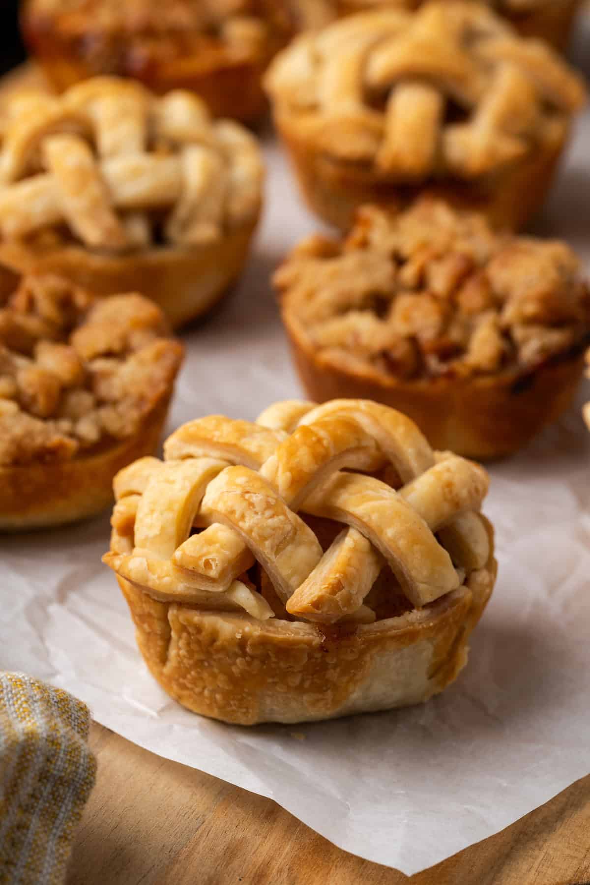 Close up of mini apple pies on a piece of parchment paper.