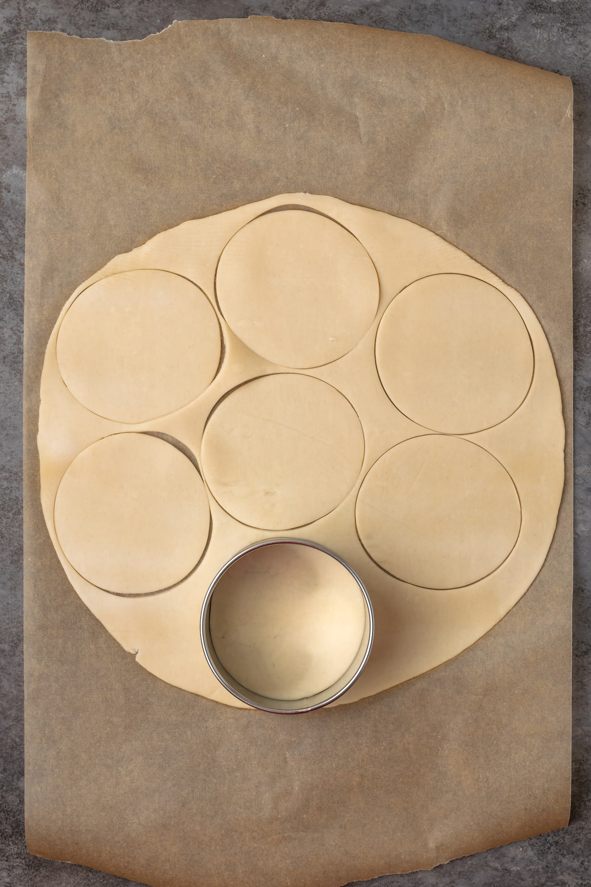 A cookie cutter is used to cut out circles from a rolled out pie crust.