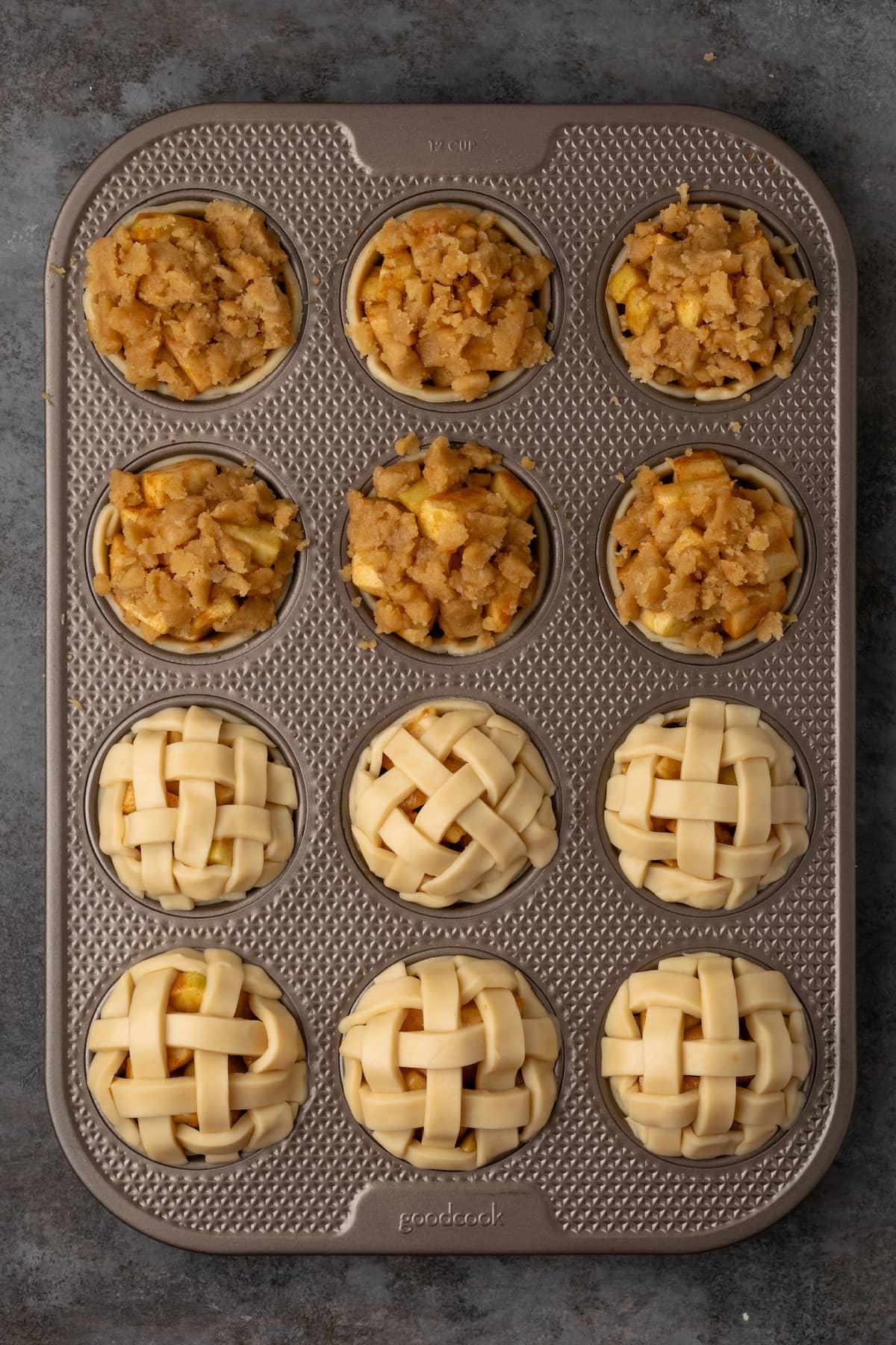 Partially assembled mini apple pies in a 12-well muffin tin.