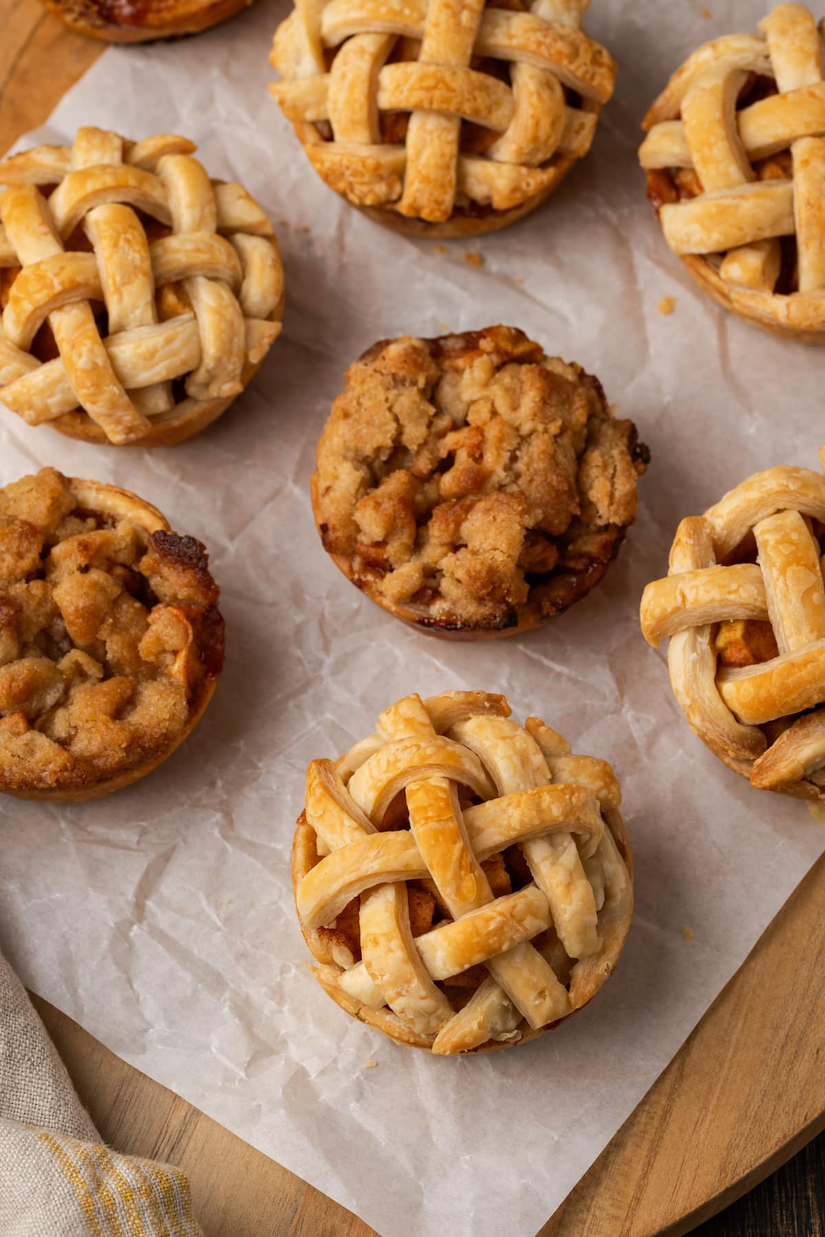 Overhead view of baked mini apple pies on a piece of parchment paper.