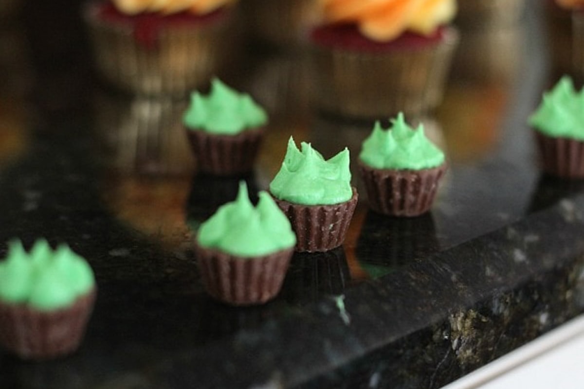 Miniature peanut butter cups topped with green frosting