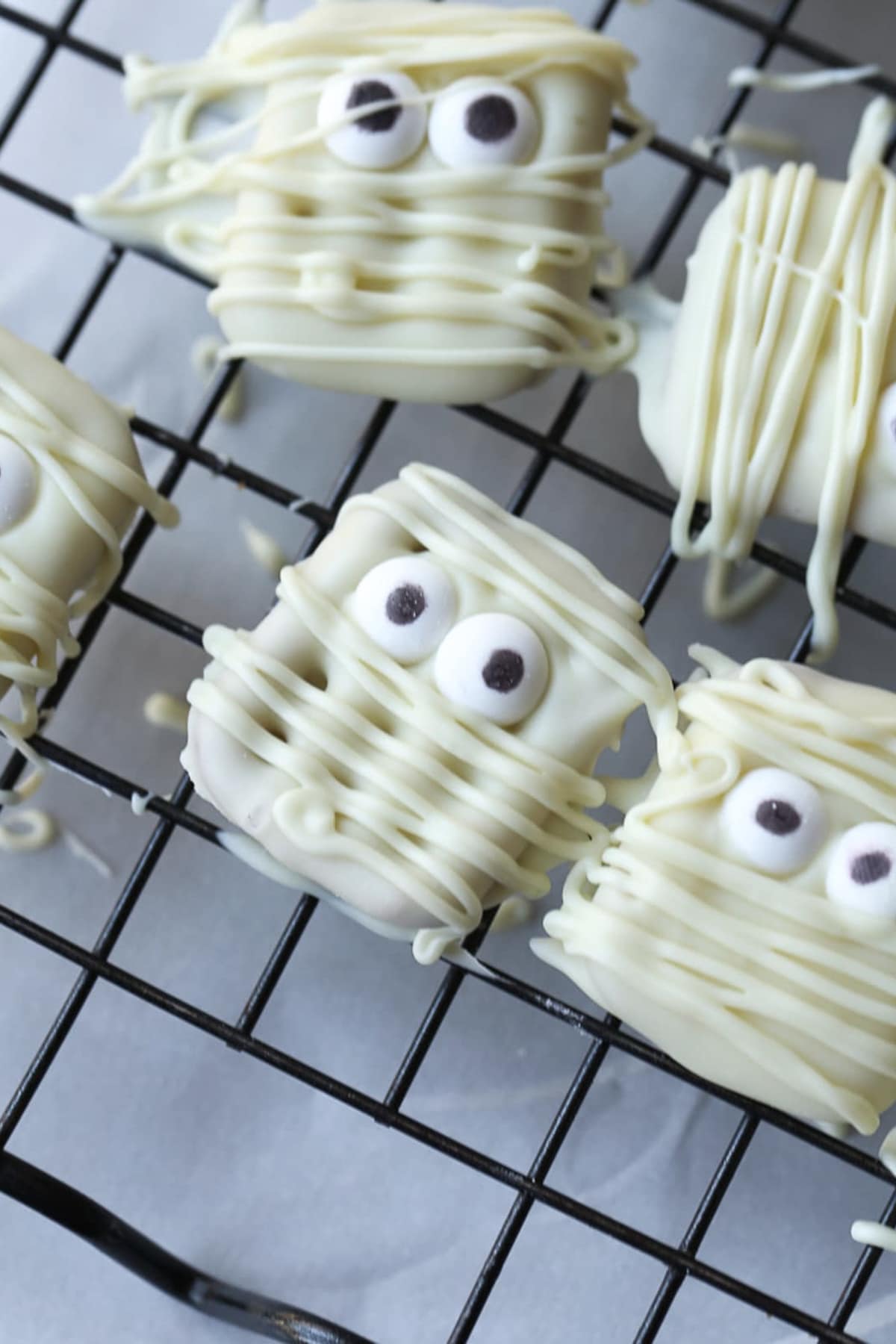 Square white chocolate pretzels with candy eyes and white chocolate drizzles made to look like mummies.