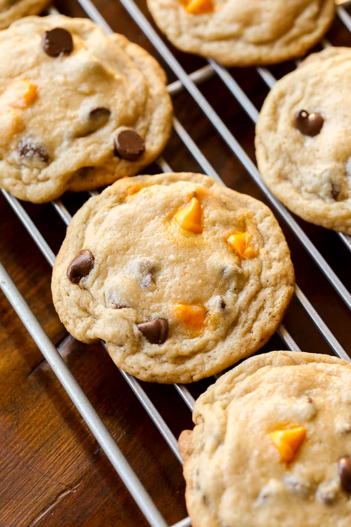 Cookies with brown and orange chips baked in on a wire cooling rack.