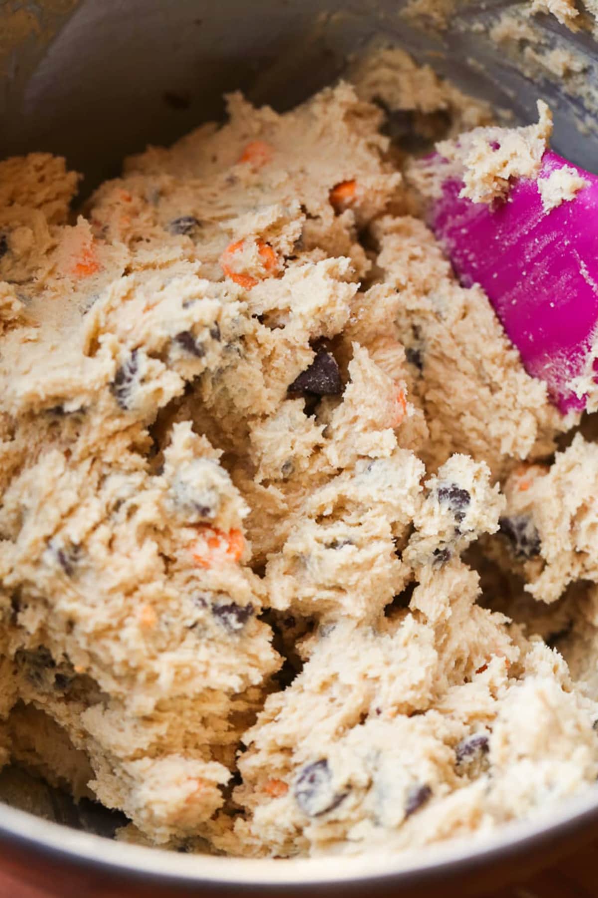 Cookie dough in a mixing bowl with a pink spatula