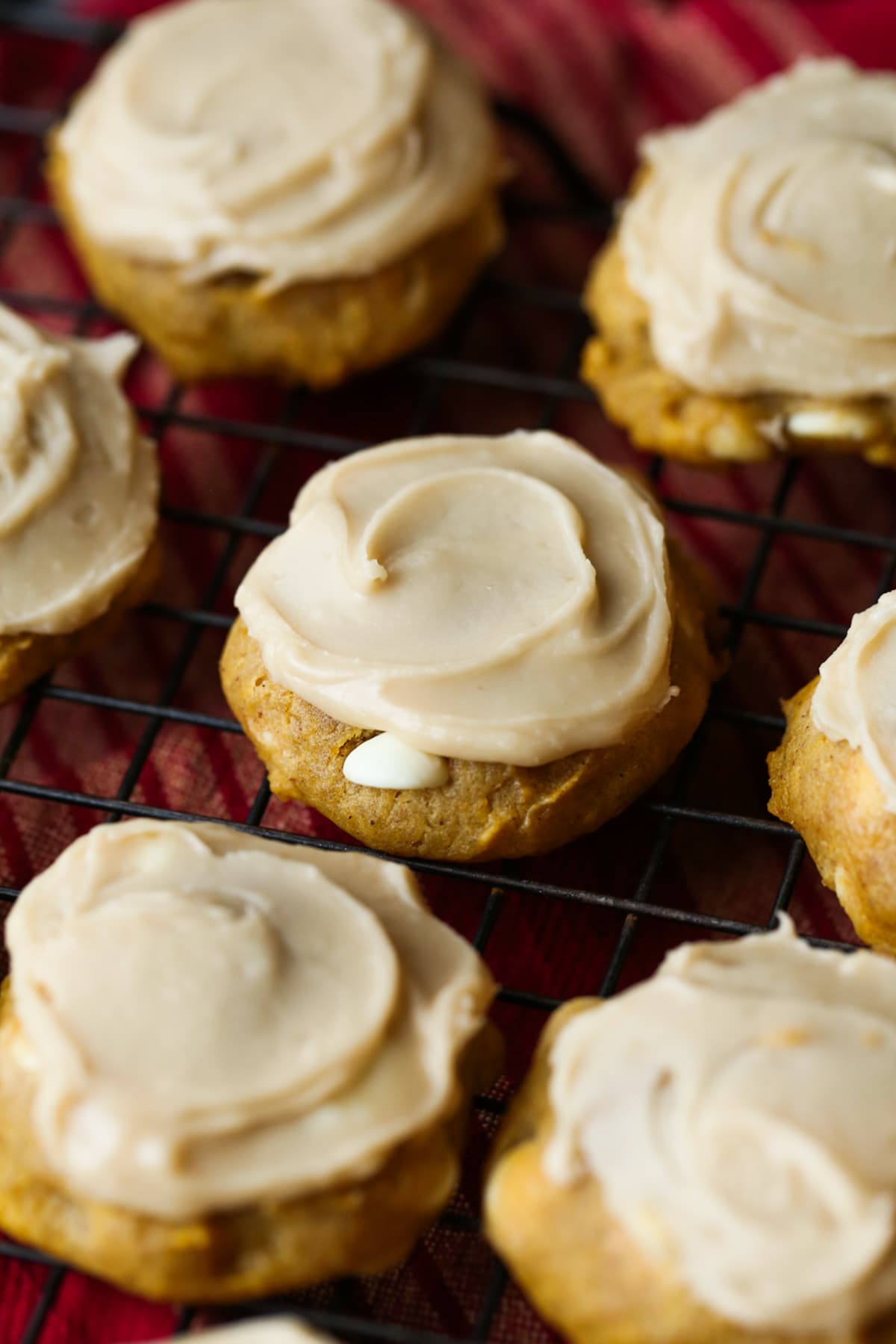 pumpkin cookies with white chocolate chips and icing on a cooling rack