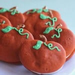 Pumpkin Whoopie Pies with pretzel stems and green frosted vines on a white plate