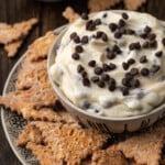 Cannoli dip served in a bowl, surrounded by cookies on a plate.