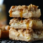 A stack of 3 Caramel Apple Cheesecake Bars on a wire rack