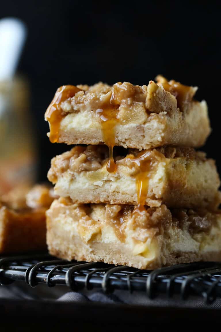 A stack of 3 Caramel Apple Cheesecake Bars on a wire rack.