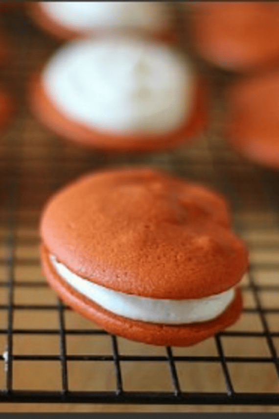 orange sandwich cookie with vanilla white filling on a cooling rack