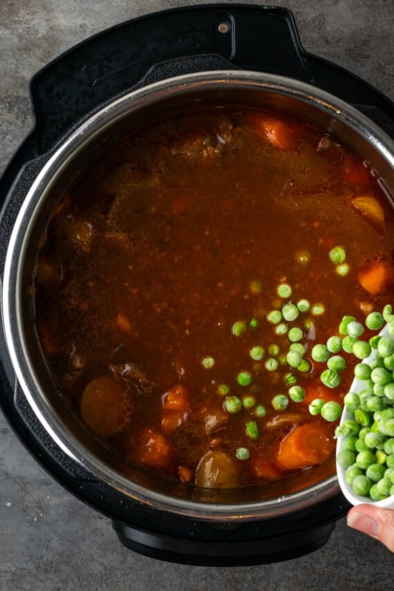 Frozen peas added to beef stew inside the instant pot.