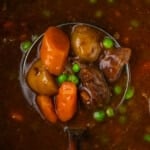 Closeup overhead view of a ladleful of beef stew held above the instant pot.