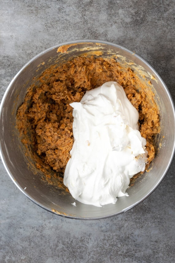 Cool Whip is added into a bowl with the peanut butter and Butterfinger mixture for the pie filling.