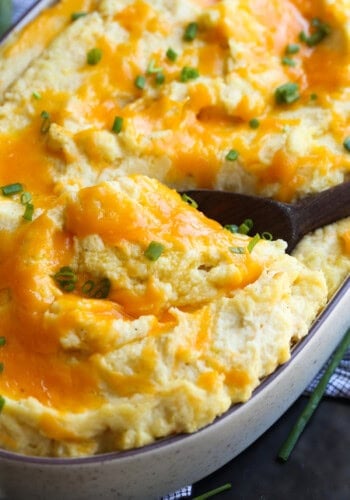 Cheese topped baked mashed potatoes with a wooden spoon to serve