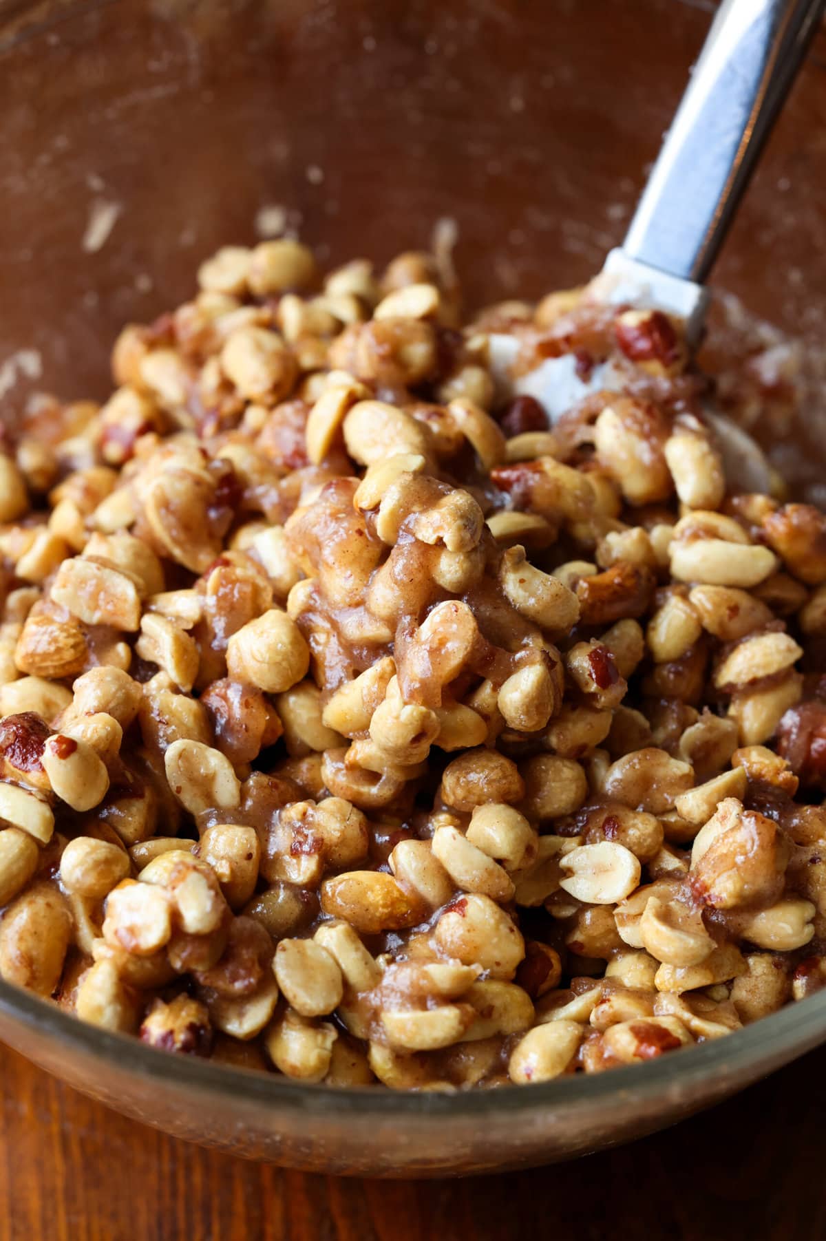 Mixing peanuts in a bowl coating them with butter, sugar mixture