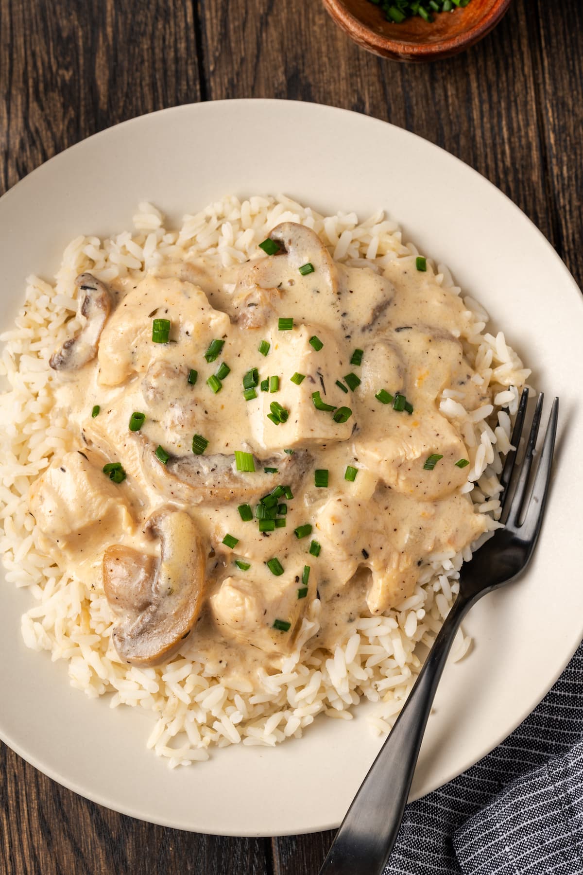 Overhead view of cream of mushroom chicken served over rice in a bowl with a fork.
