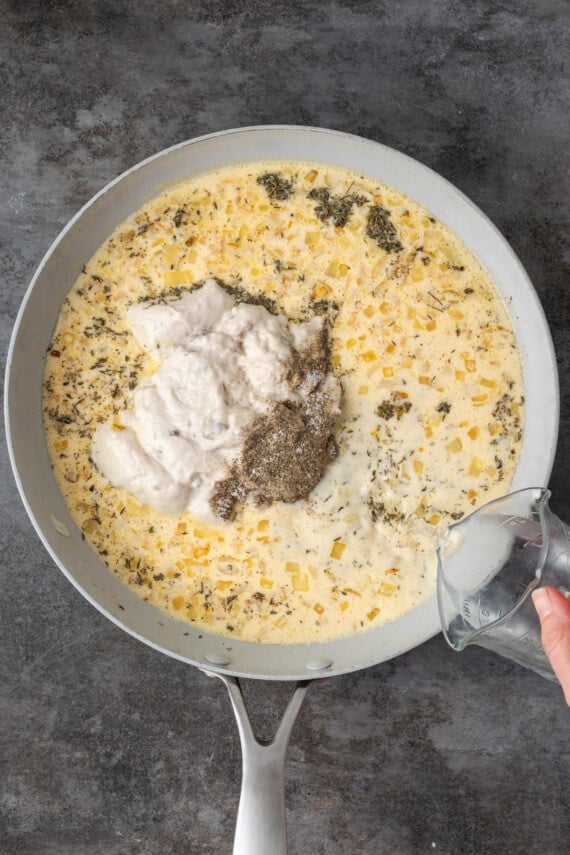 Cream of mushroom sauce ingredients added to a skillet.