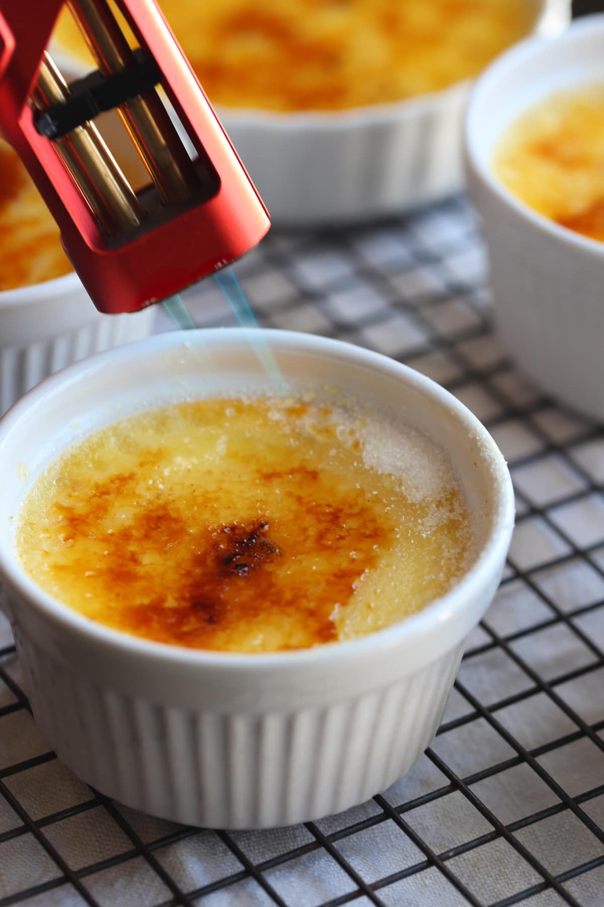Using a kitchen torch to brûlée the sugar, melting it and caramelizing so it forms a crispy sugar top