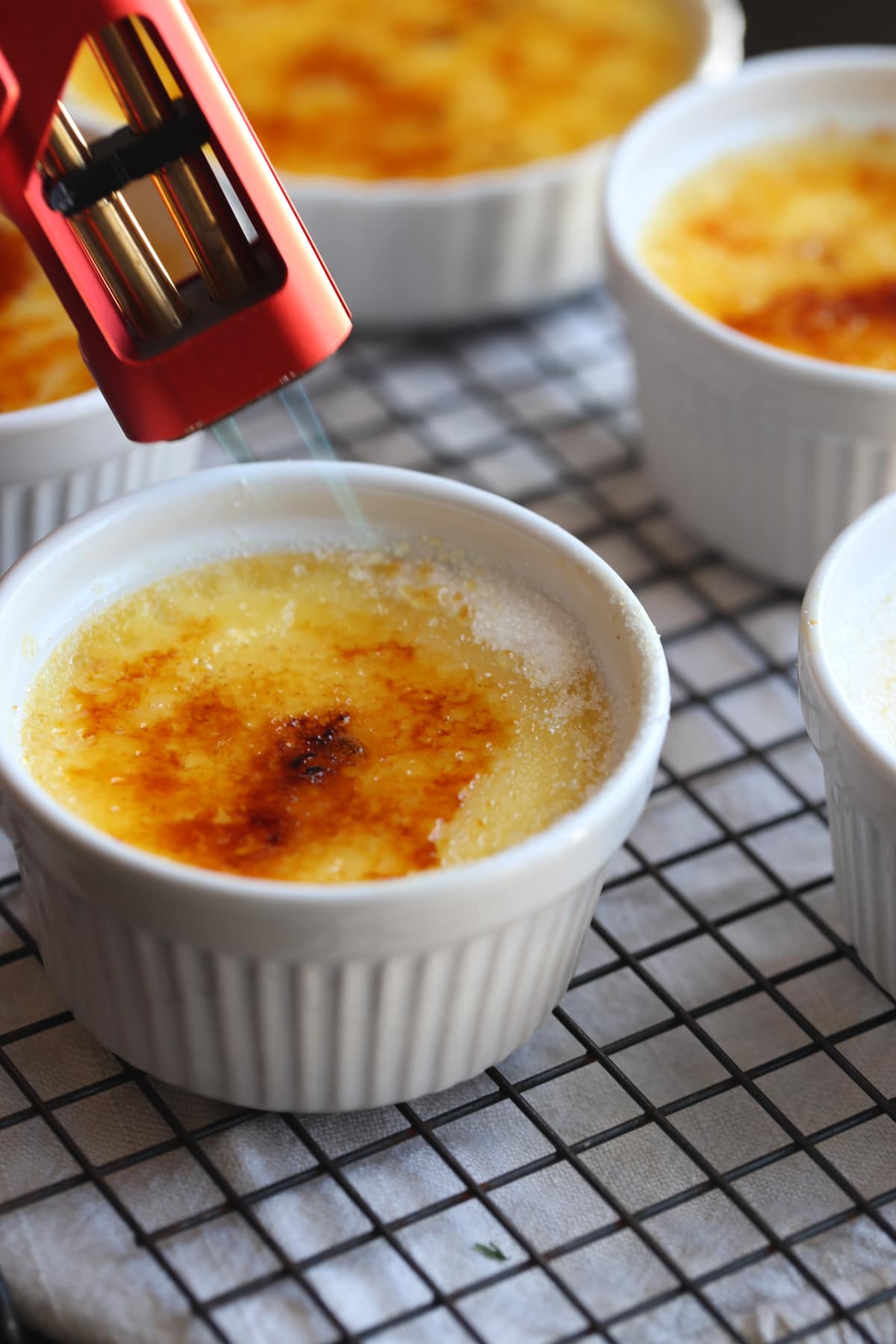 using a kitchen torch to brûlée the sugar, melting it and caramelizing so it forms a crispy sugar top