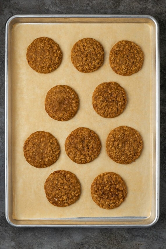 Baked oatmeal cookies on a parchment-lined baking sheet.